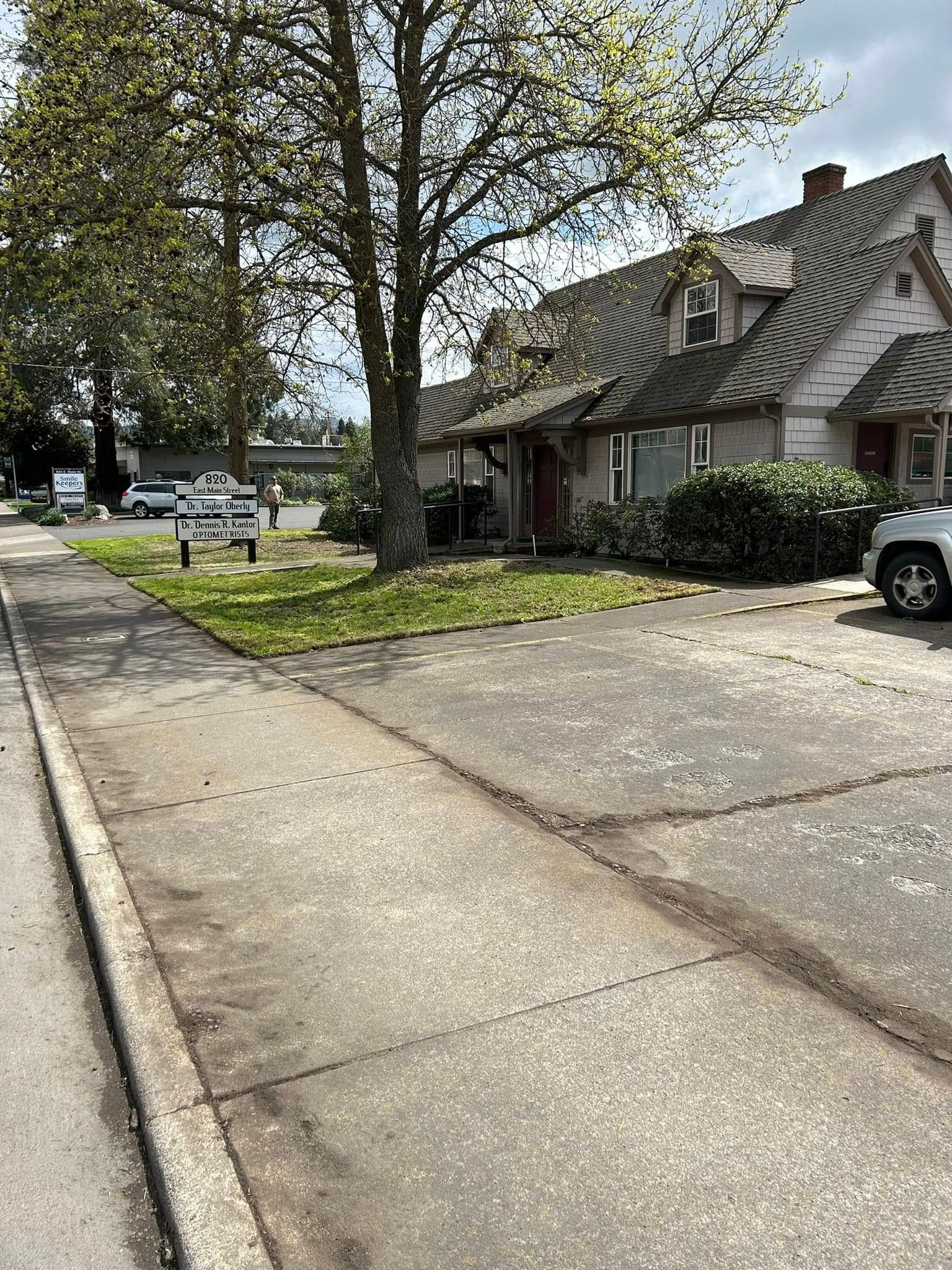 A house is sitting on the corner of a street next to a parking lot.