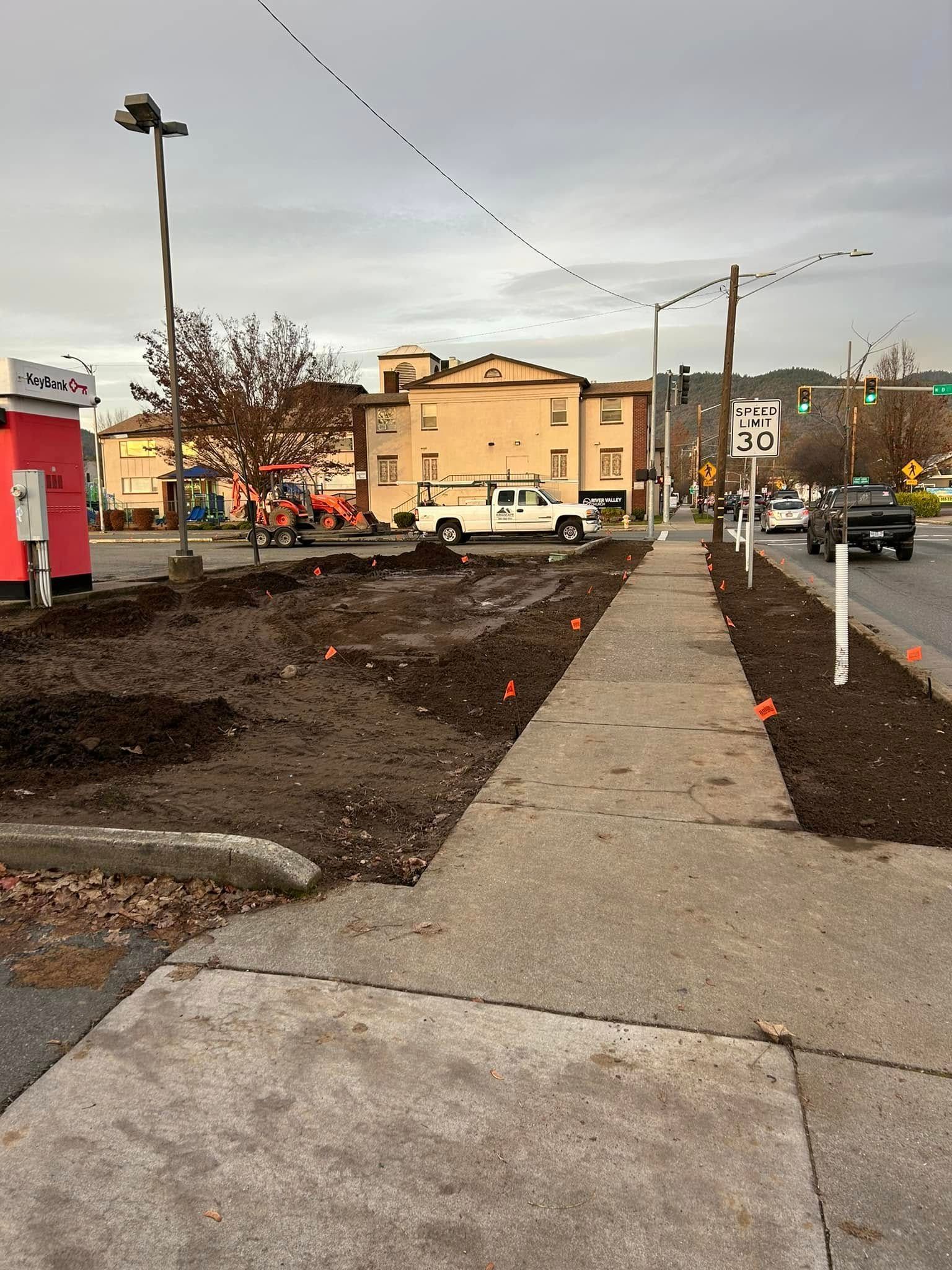 A white truck is parked on the side of the road next to a sidewalk.