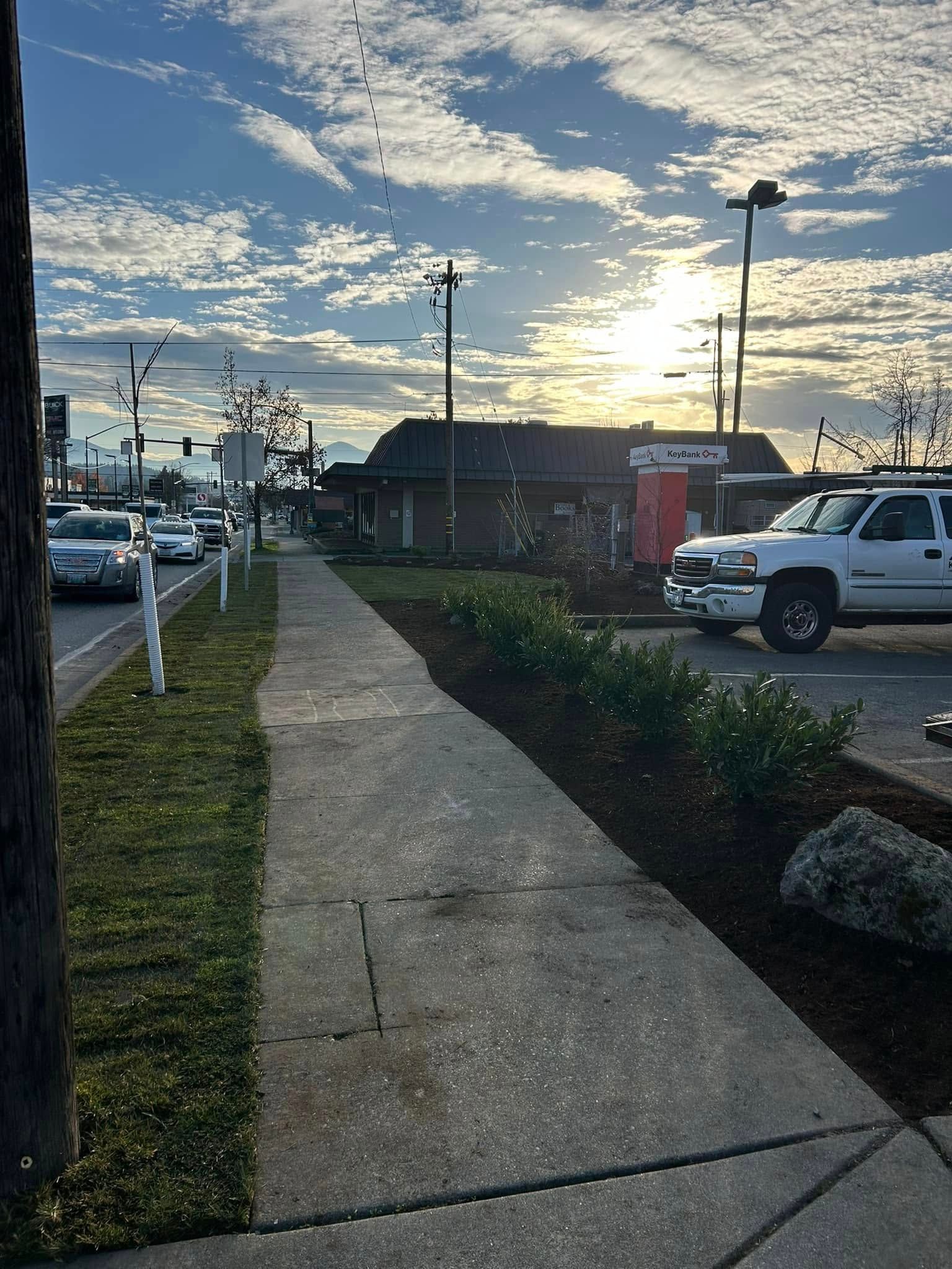 A white truck is parked on the side of the road next to a sidewalk.
