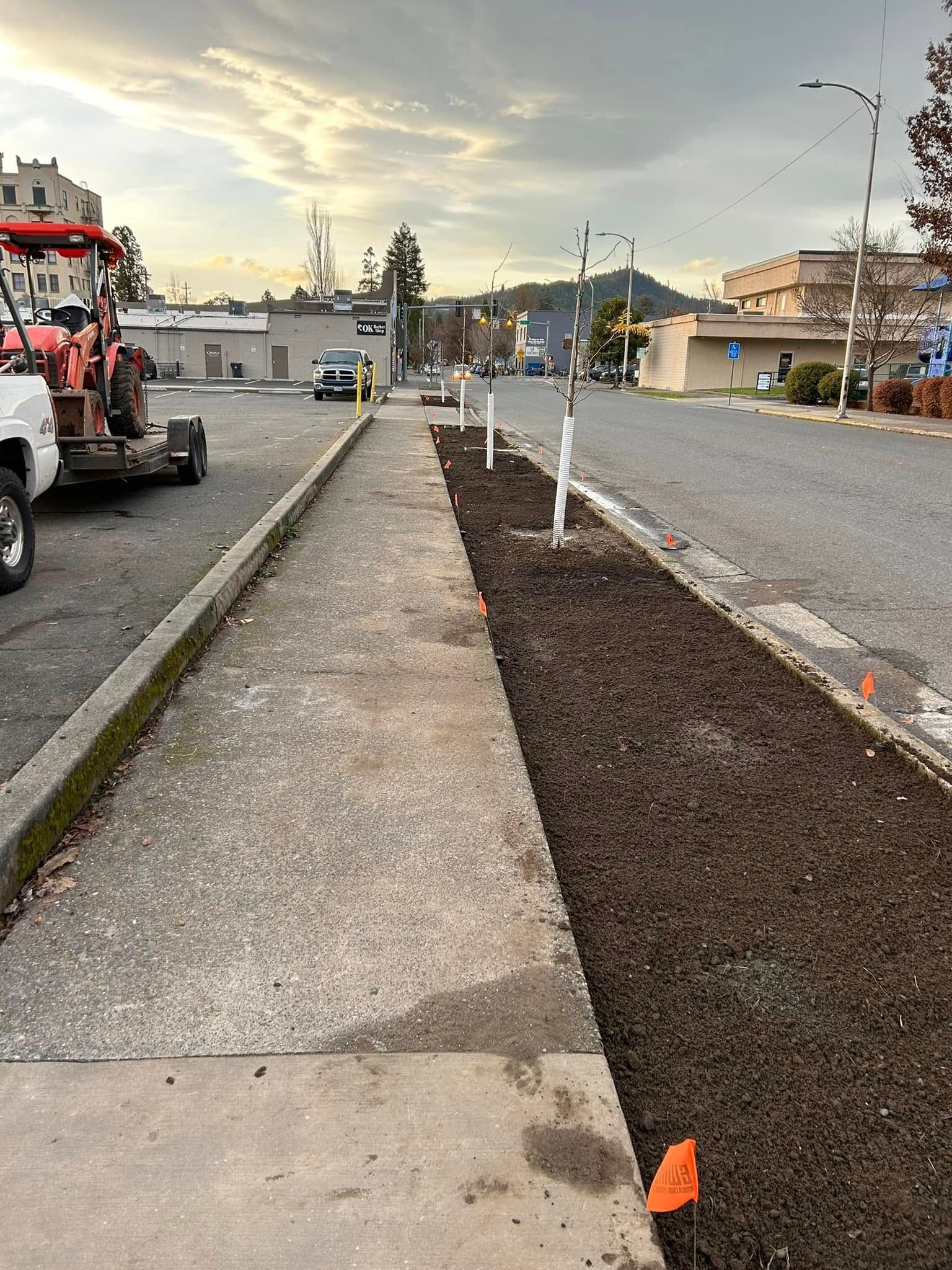 A sidewalk with a tractor parked on the side of it.