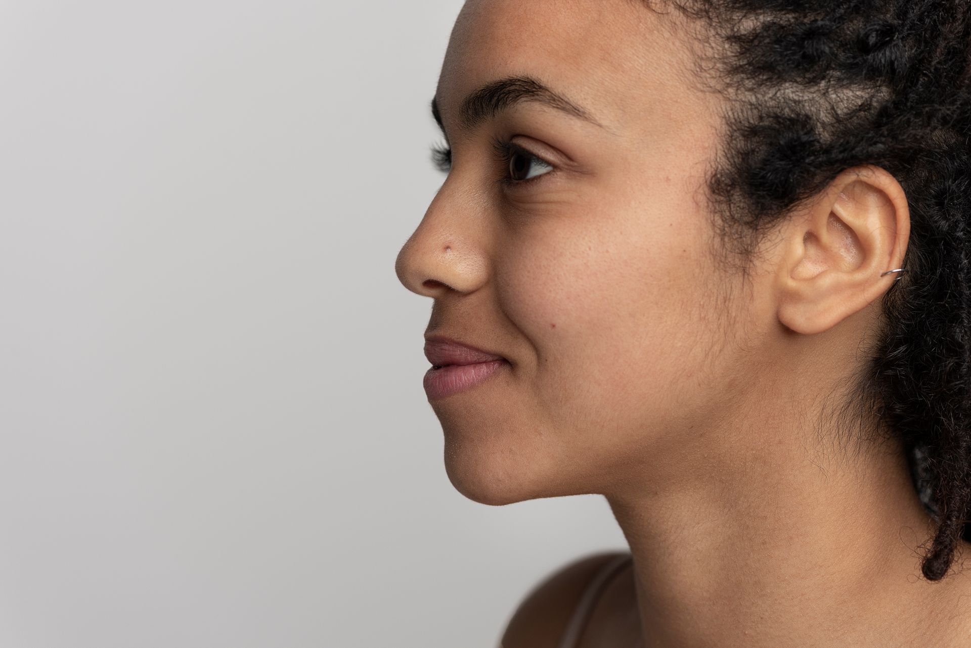 A close up of a woman 's face and perfect jawline with a smile on her face.