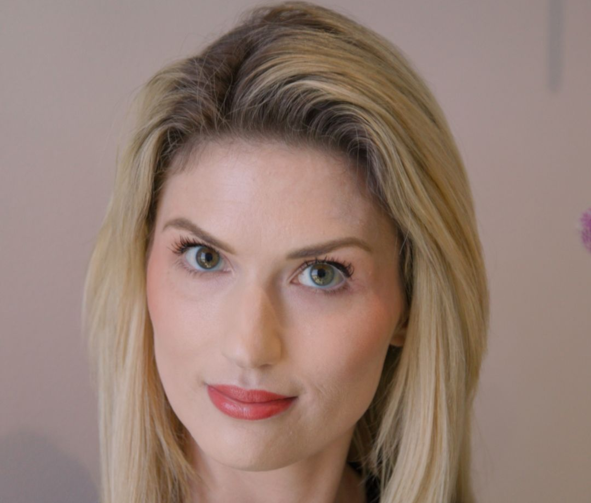 Blonde woman with fair skin and green eyes looking at the camera.