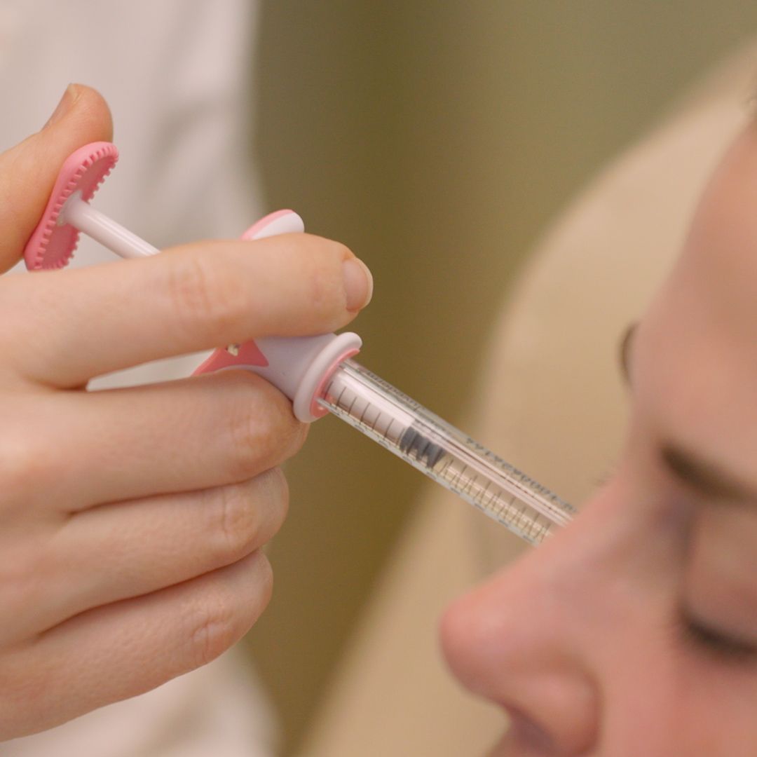 A close up of a person holding a syringe in their hand.