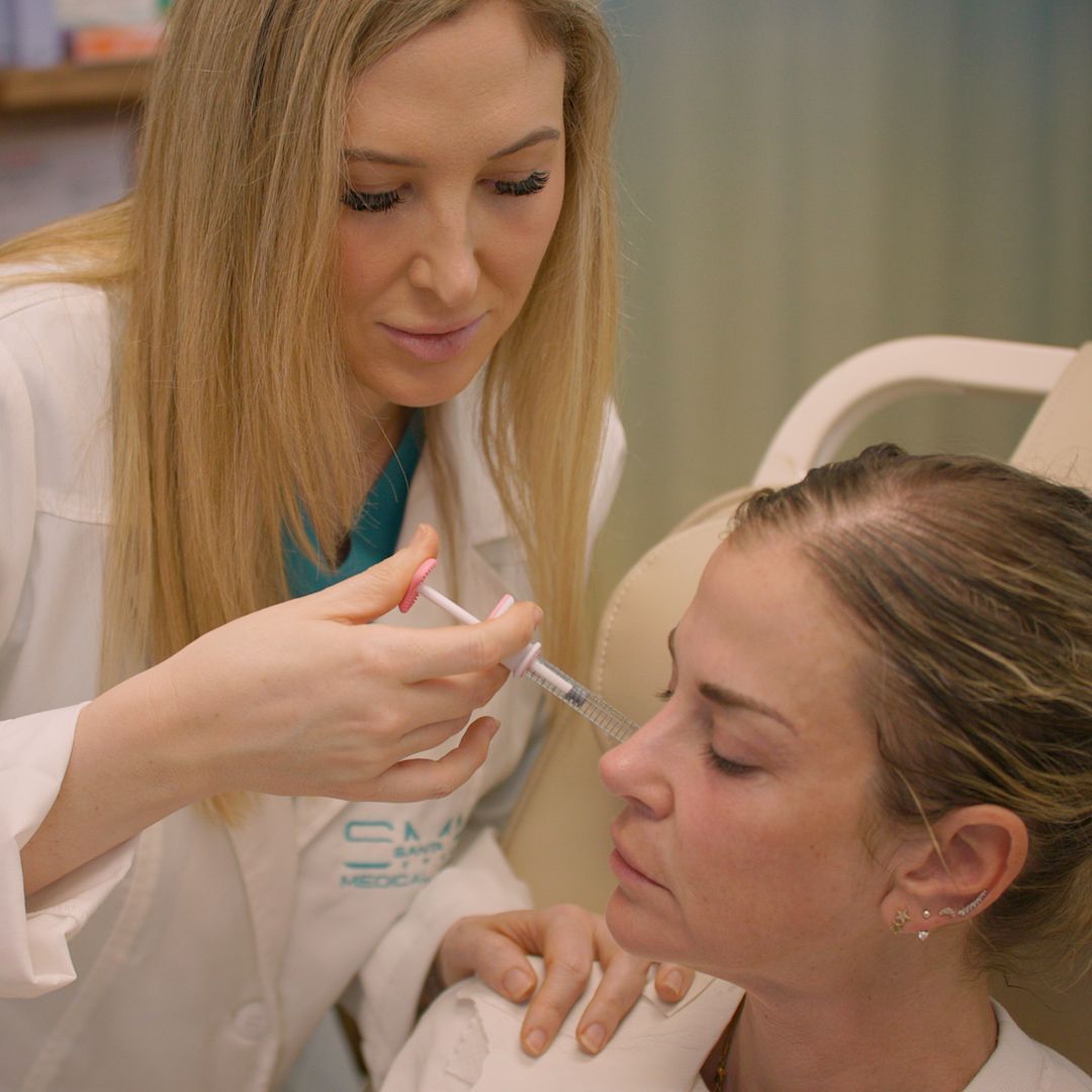 A woman is getting an injection in her face from a doctor.
