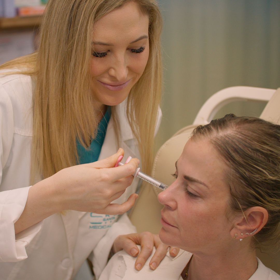 A woman is getting an injection in her face from a doctor.