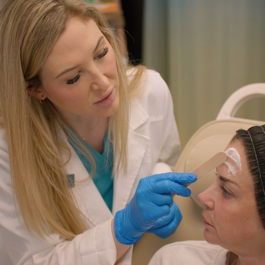 A doctor is applying a bandage to a patient 's forehead.