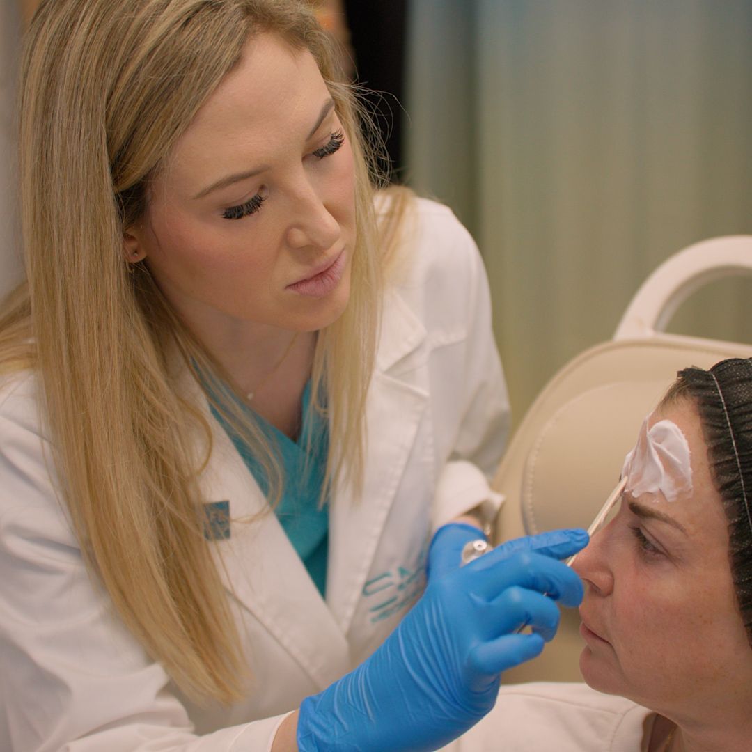 A woman is getting her eyebrows done by a doctor.