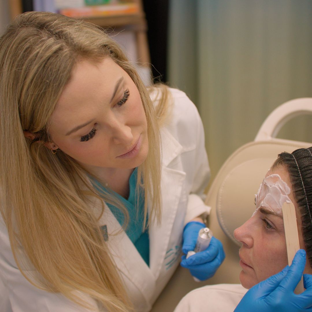 A woman is getting a facial treatment from a doctor.
