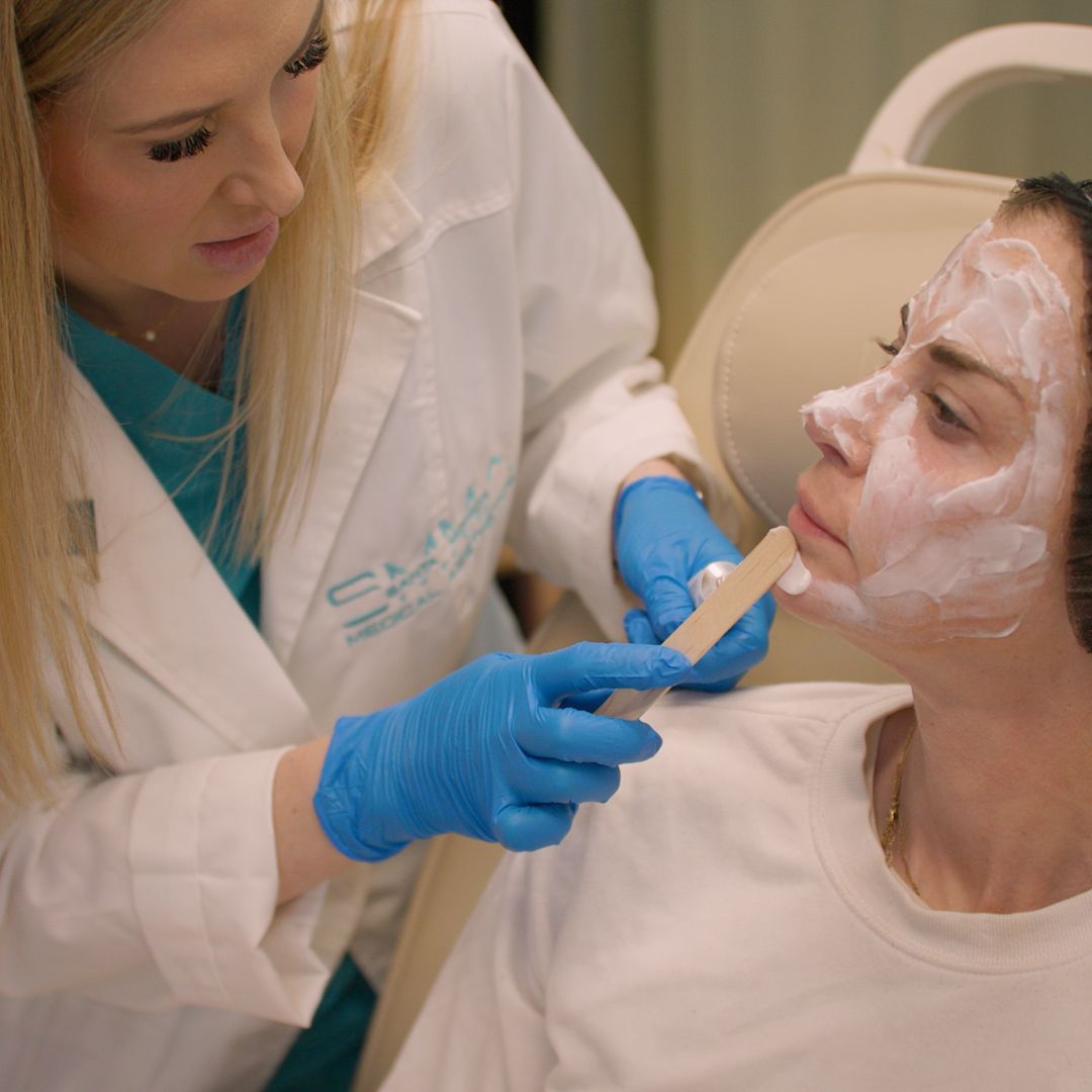 A woman with a mask on her face is being examined by a doctor.