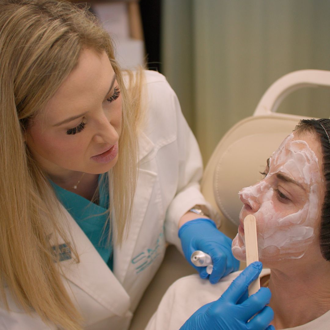 A woman with white paint on her face is being examined by a doctor.