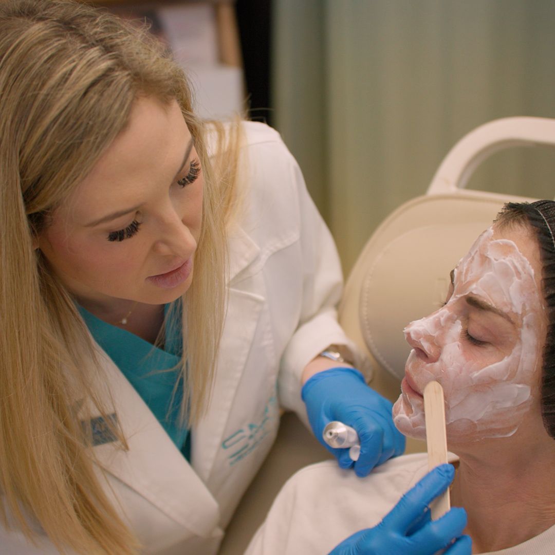 A woman is getting a facial treatment from a doctor