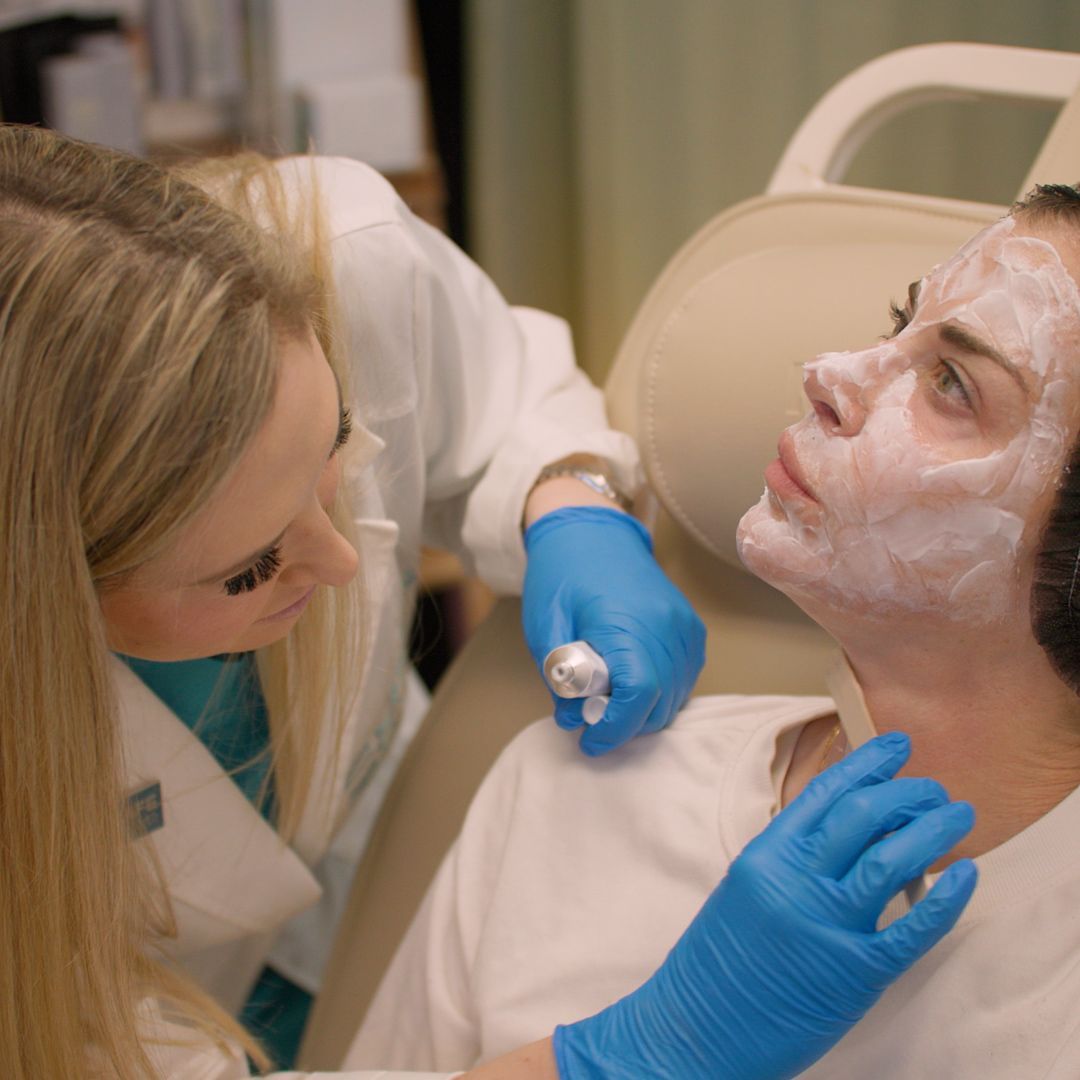 A woman with a mask on her face is being examined by a doctor.