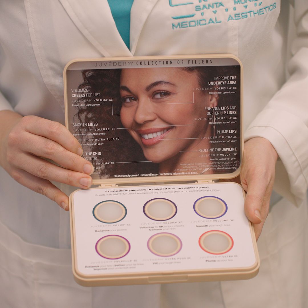 A woman in a white coat is holding a box with a picture of a smiling woman on it