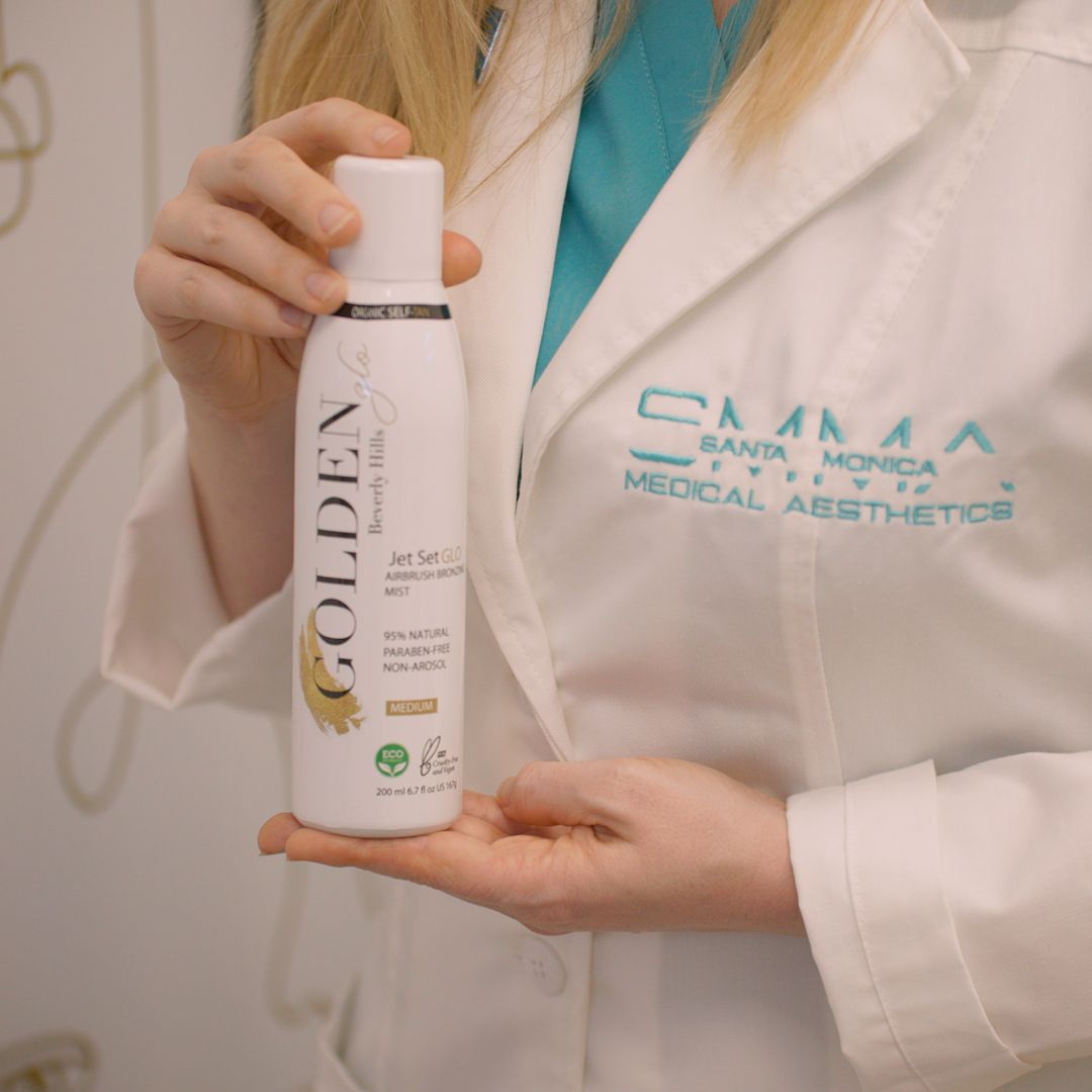 A woman in a white coat is holding a bottle of golden