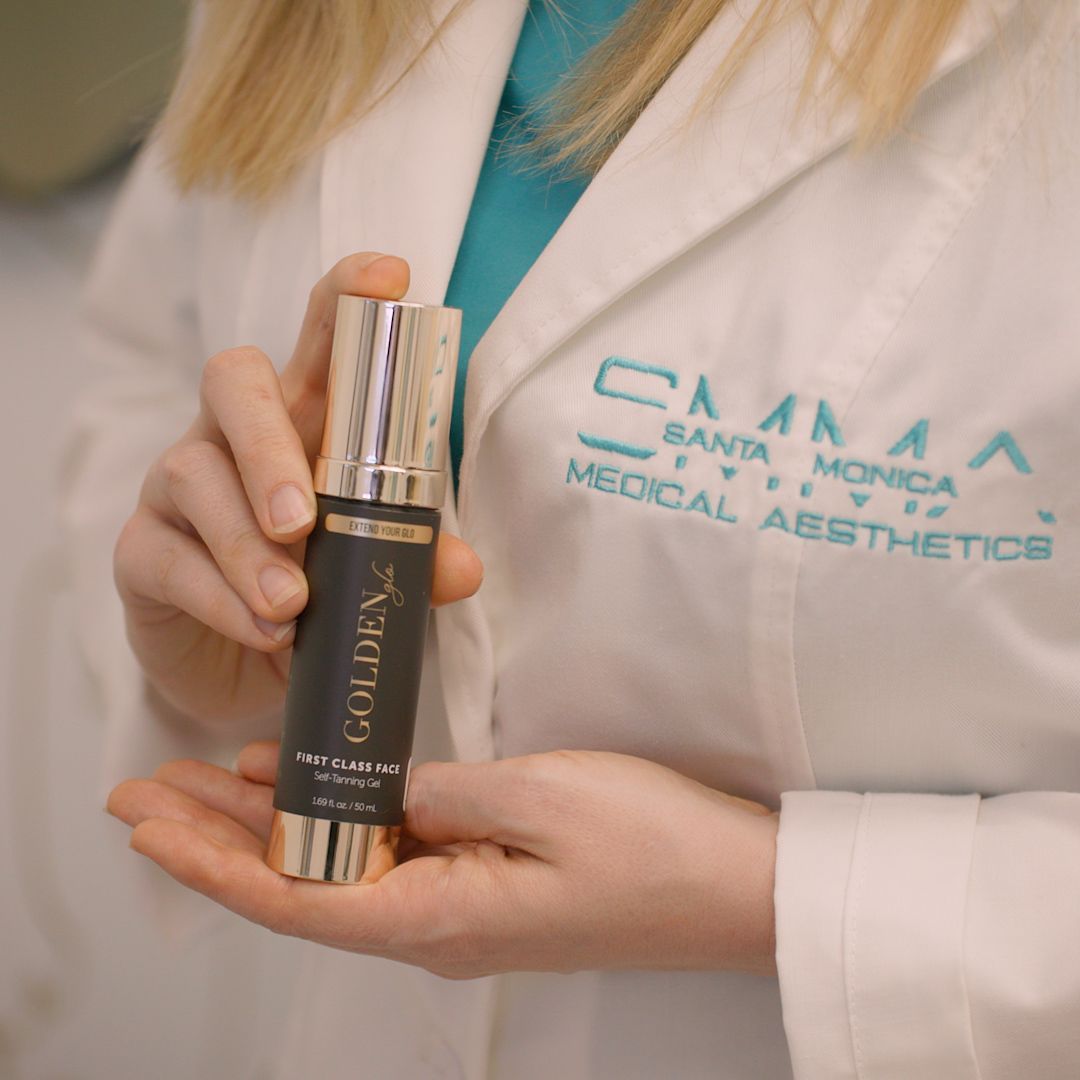 A woman is holding a bottle of golden medical aesthetics