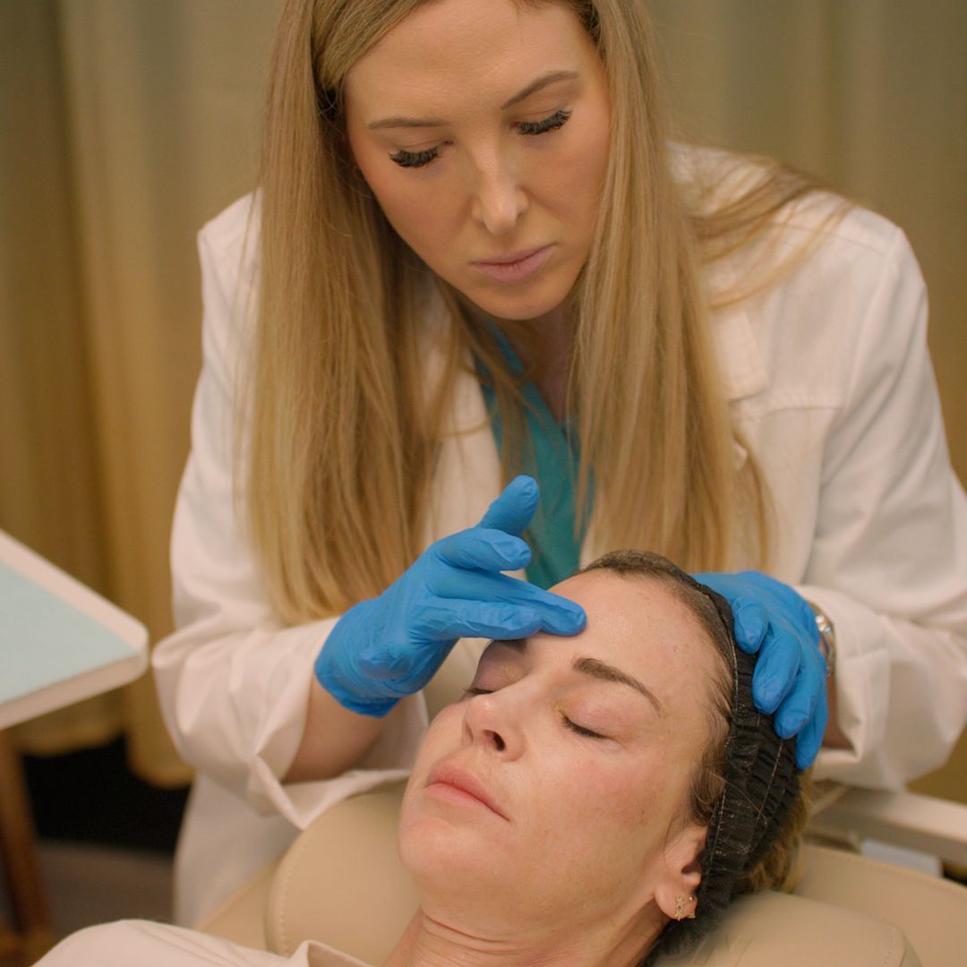 A woman is getting a facial treatment from a doctor.