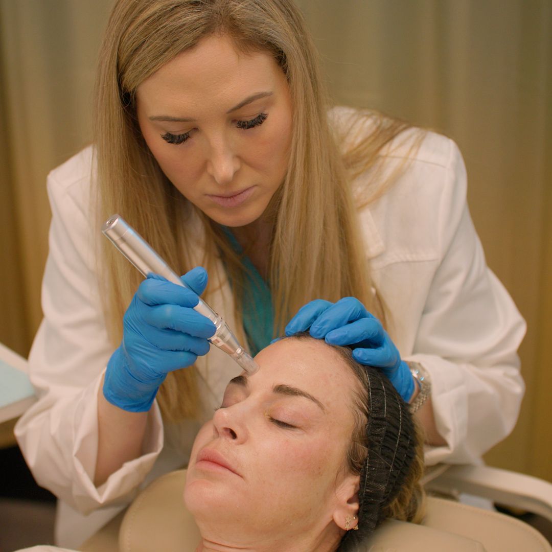 A woman is getting a tattoo on her face by a doctor.