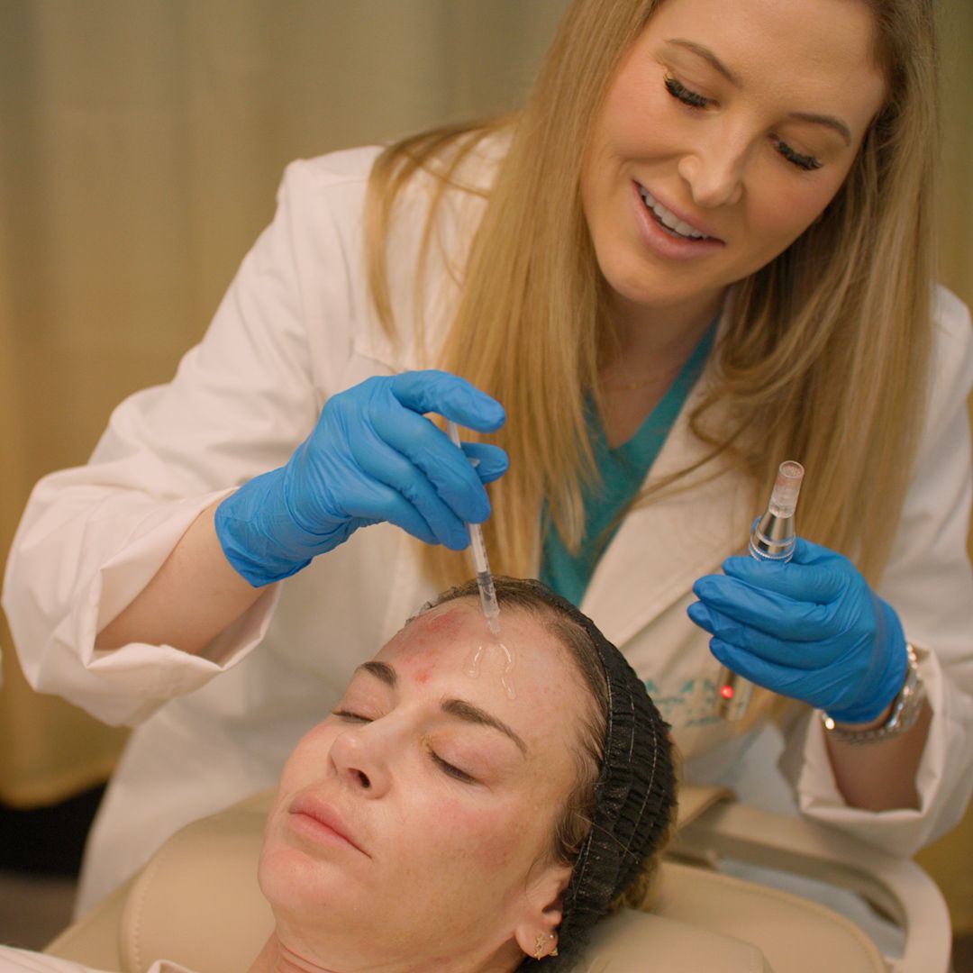 A woman is getting a botox injection on her forehead.