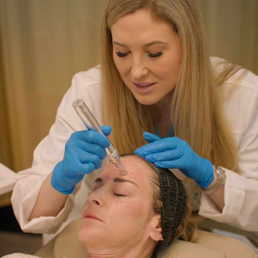 A woman is getting a tattoo on her forehead.