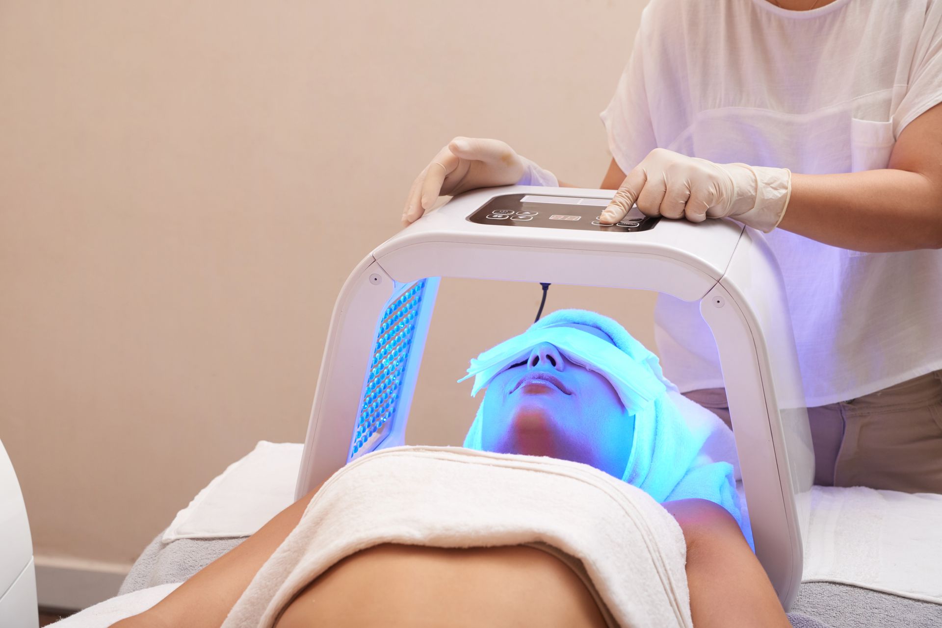 A woman is getting a blue light treatment on her face.