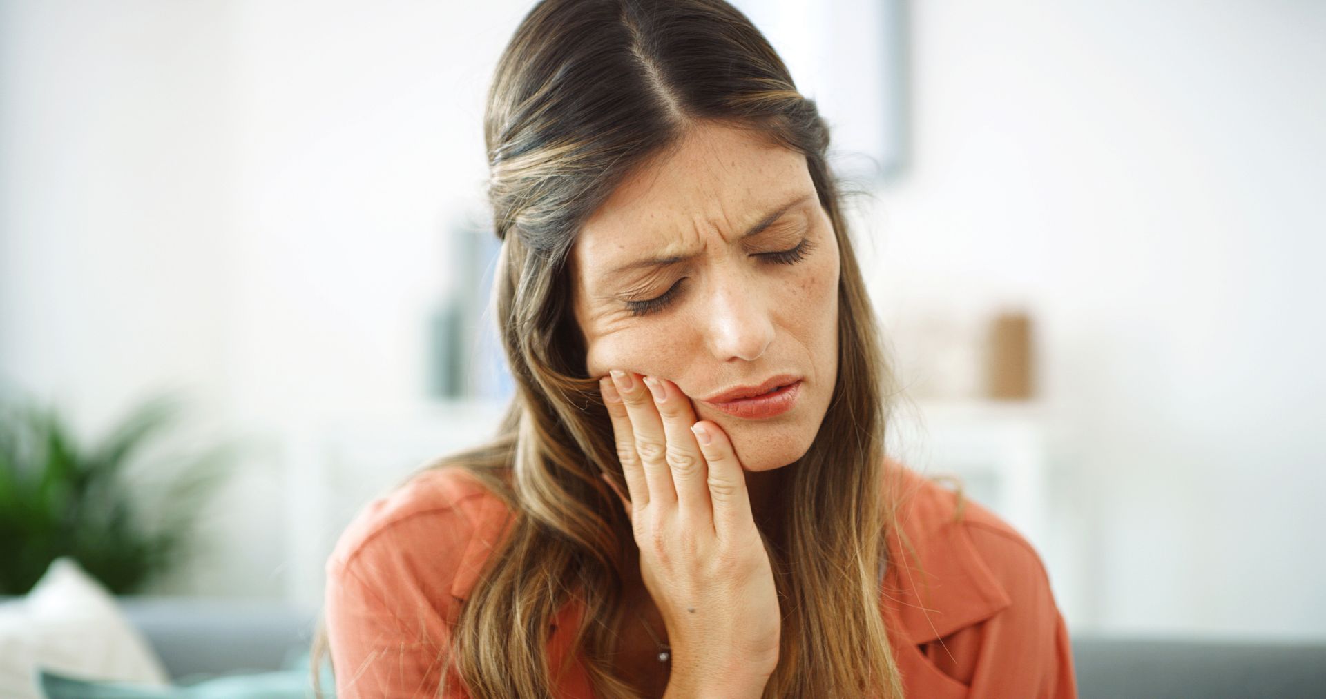 Person touching their cheek as they experience tooth pain that may need a root canal.