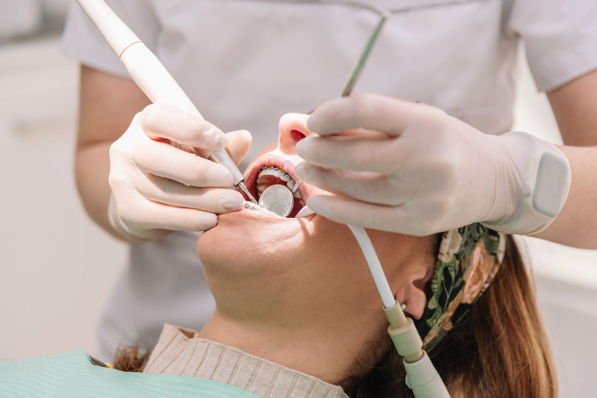 Dentist performing dental exam on female patient using professional tools in a modern dental clinic.