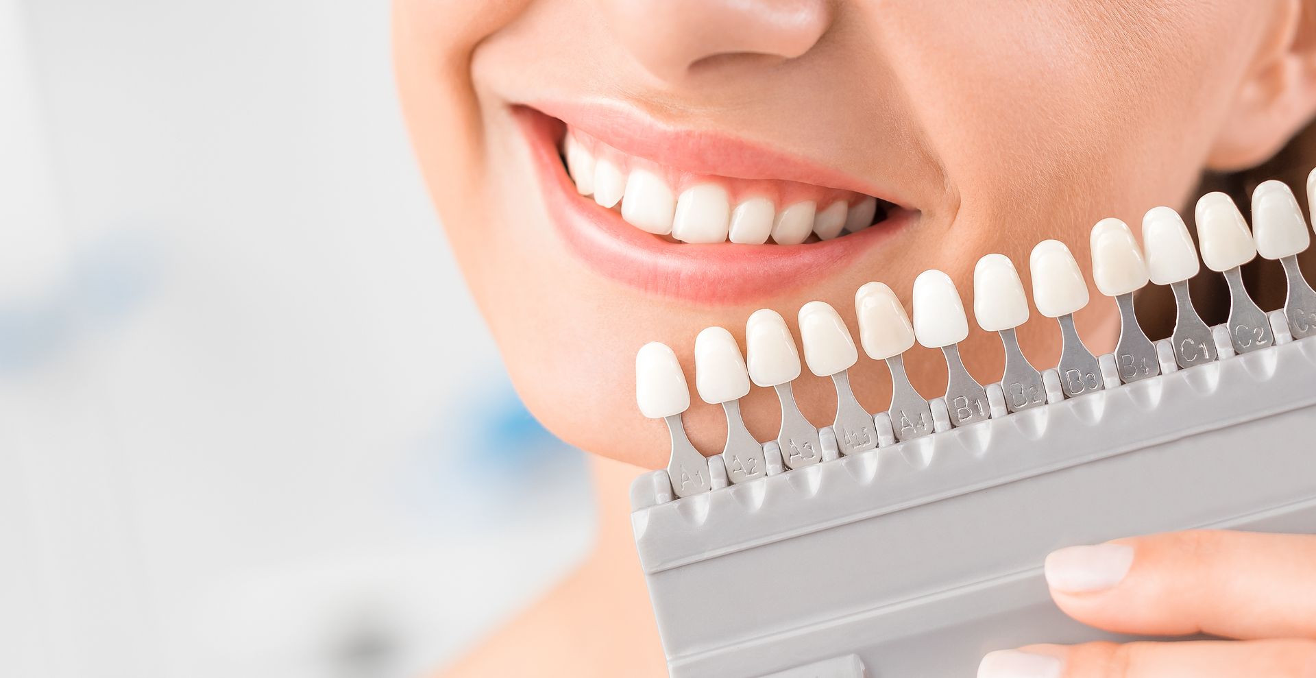 Smiling woman holding a dental shade guide for dental implants at High Point Smile Dentistry in High