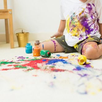 child creating mess with paint on white carpet