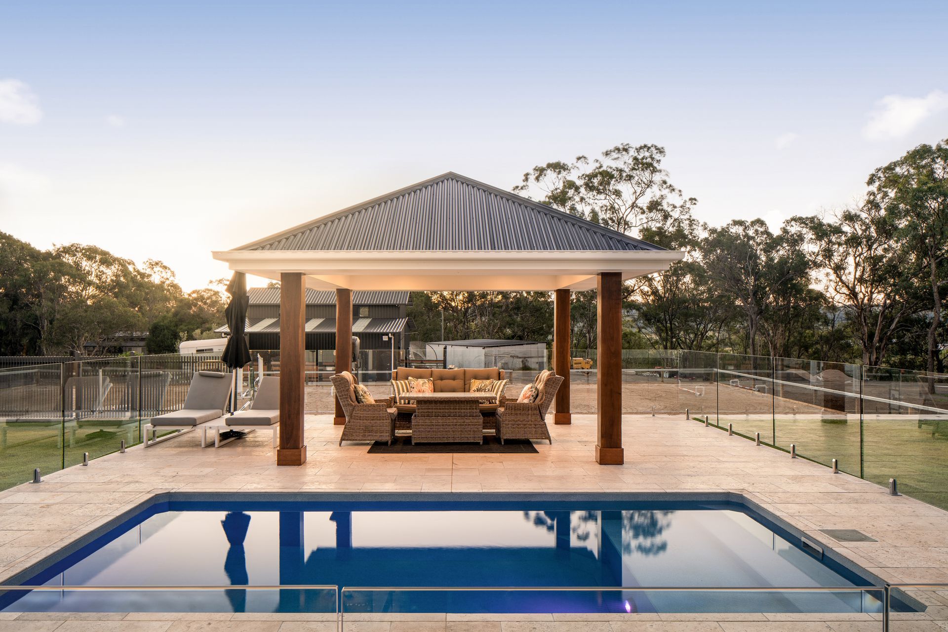 a gazebo with a table and chairs next to a large swimming pool .