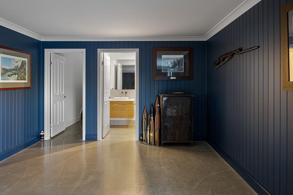 a hallway with blue walls and a concrete floor leading to a bathroom .