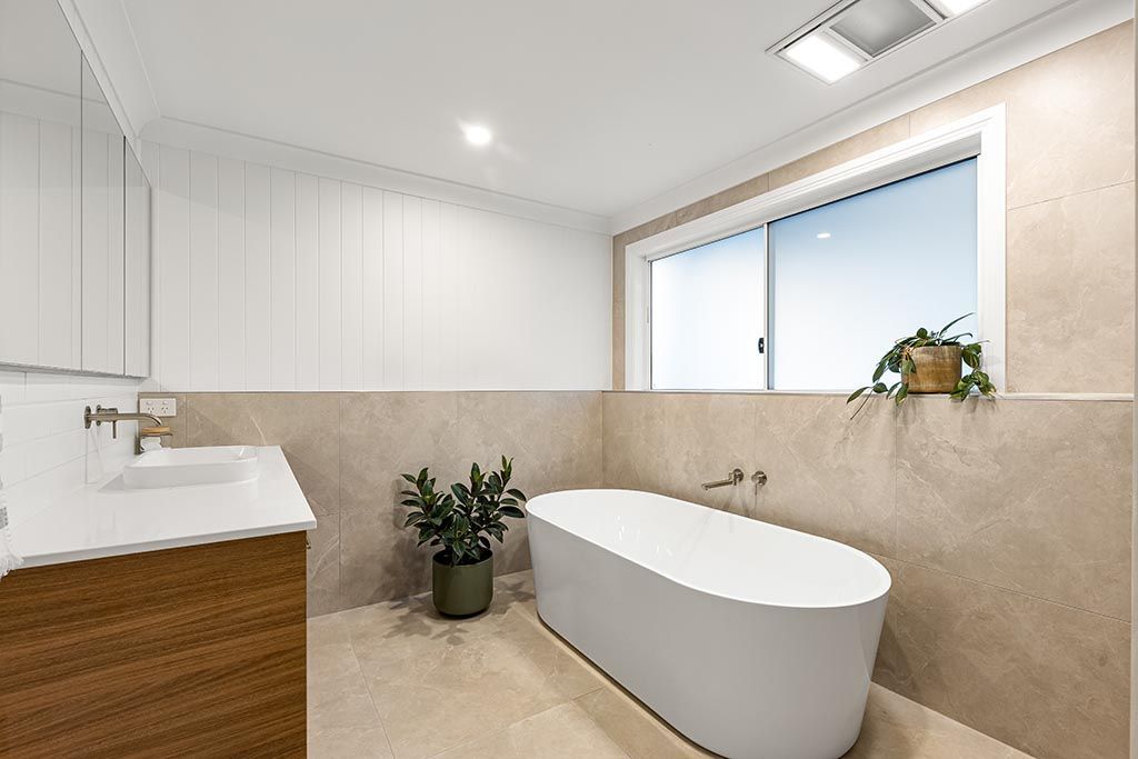 a bathroom with a tub , sink , mirror and window .