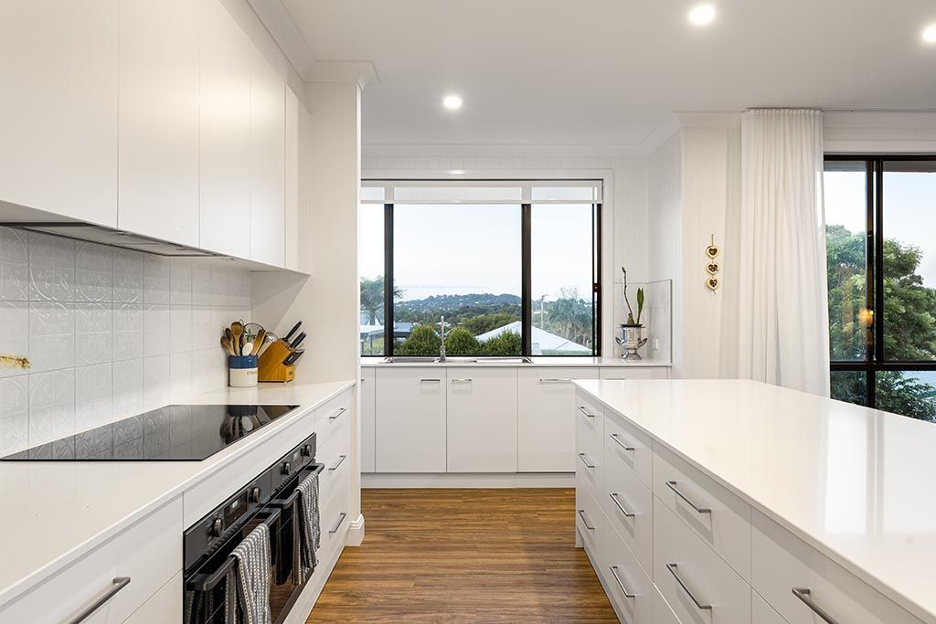 a kitchen with white cabinets , a stove top oven , and a large island .
