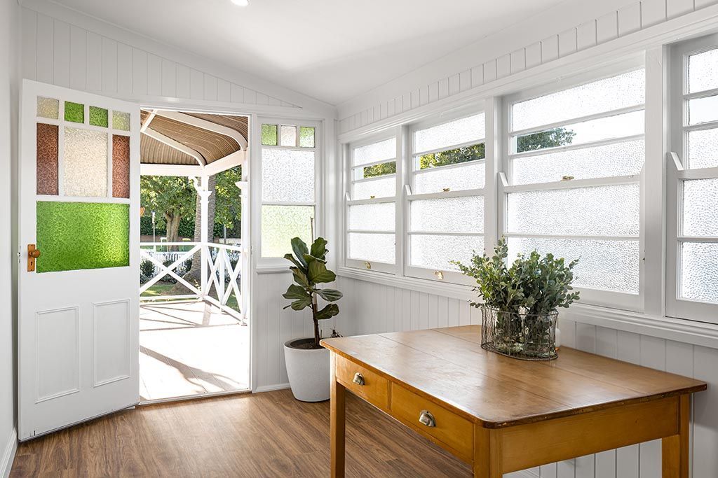 a wooden table with a potted plant on it in a room with lots of windows .