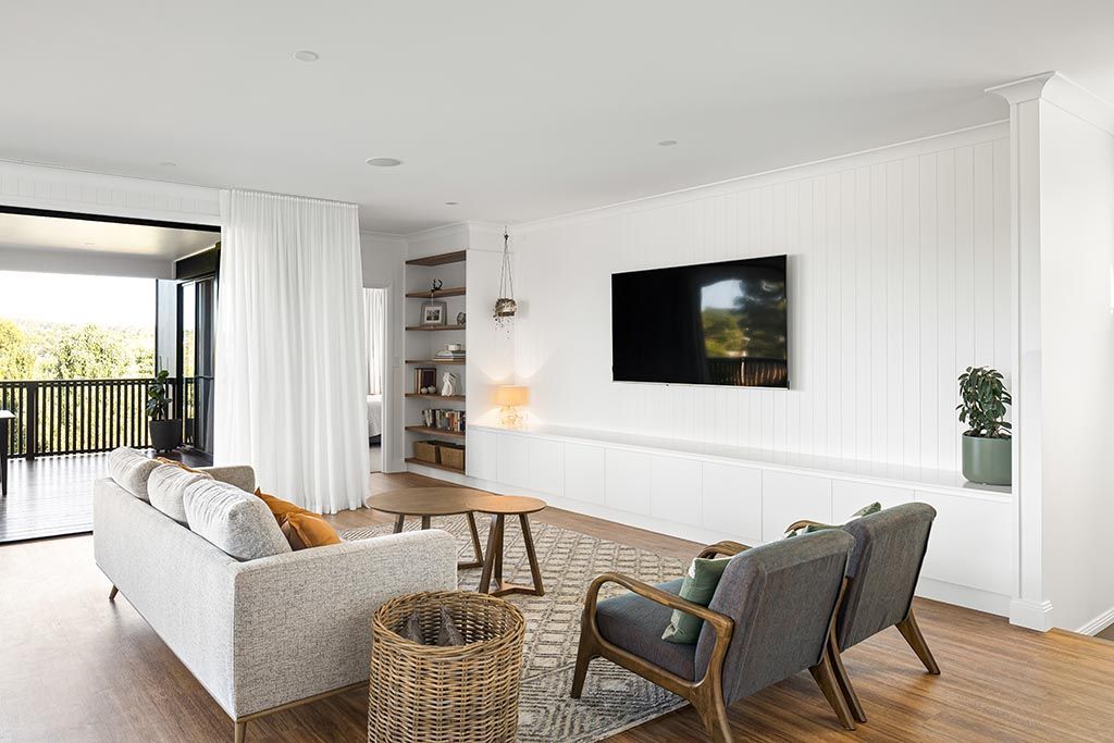 a living room with a couch , chairs , table and television .
