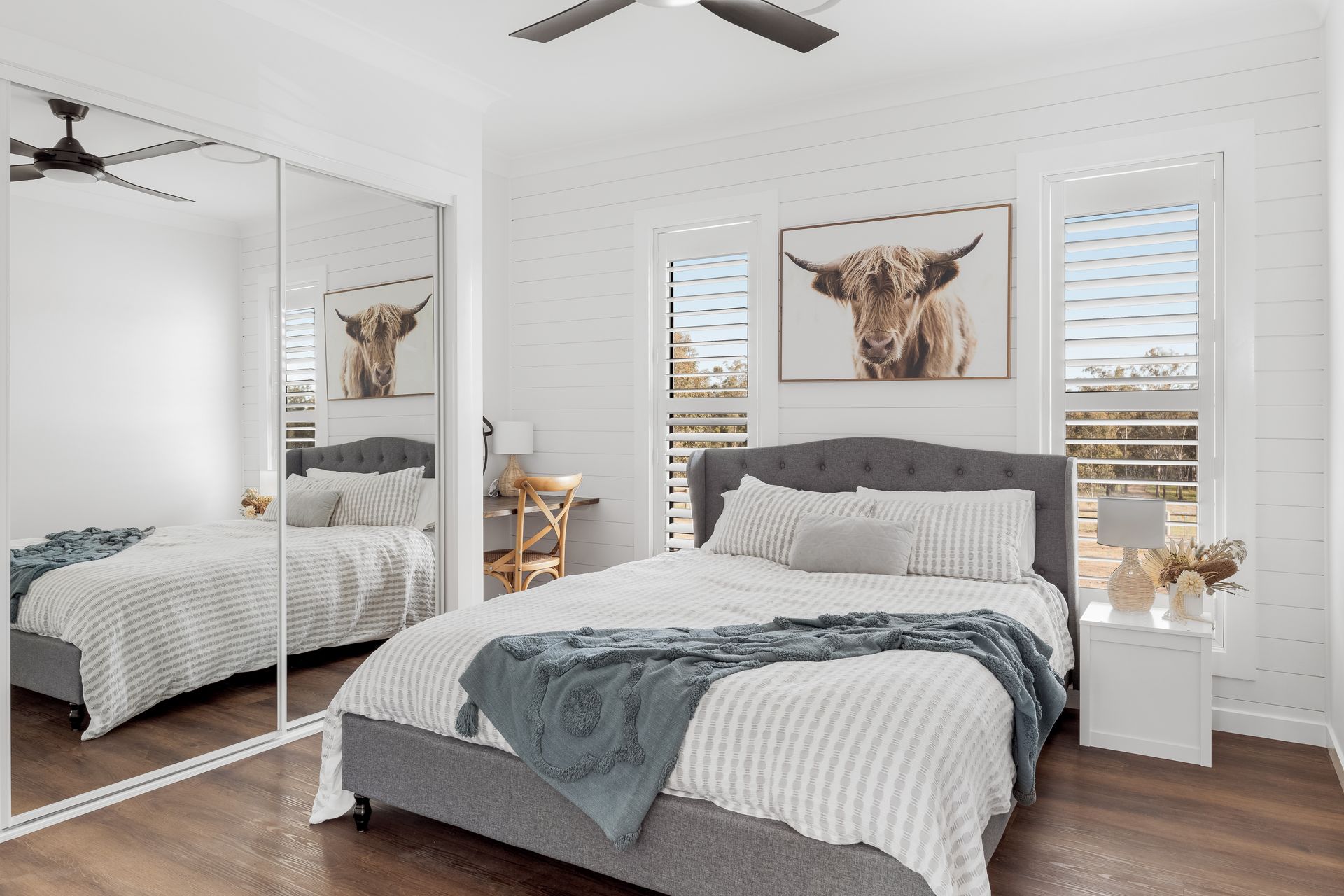 a bedroom with two beds , a ceiling fan , and a large mirror .
