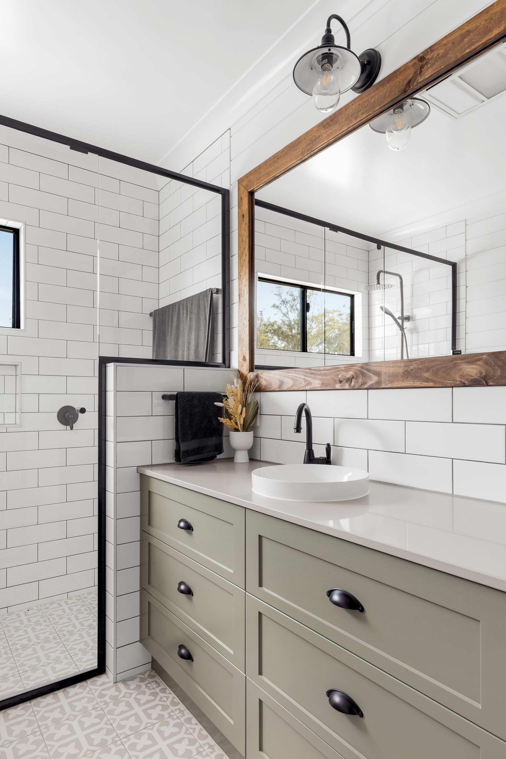A bathroom with a sink , mirror and walk in shower.