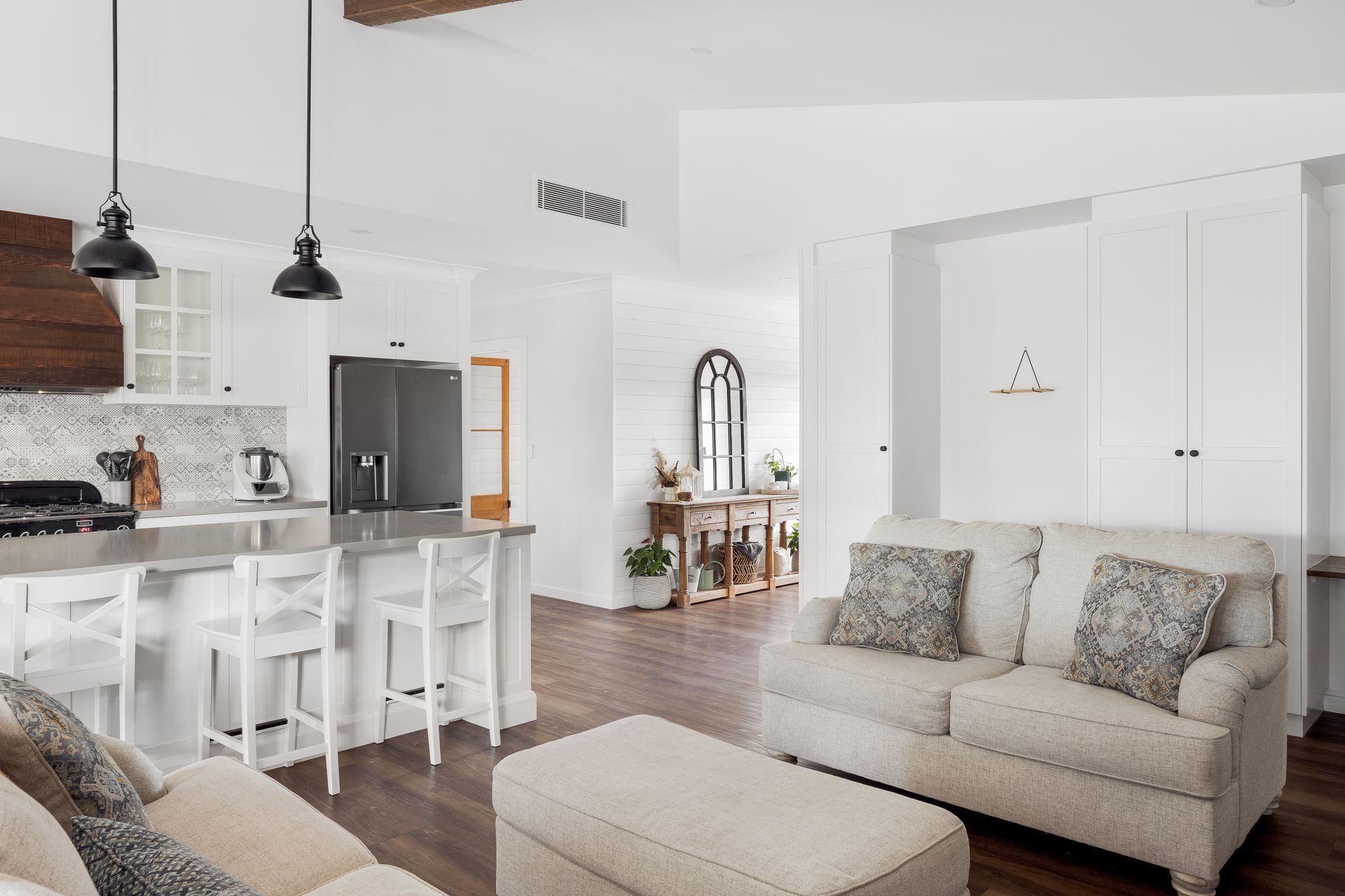 a living room with a couch , ottoman , and kitchen .