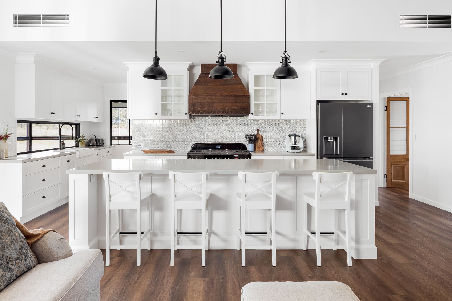 a kitchen with white cabinets , stools , a stove and a refrigerator