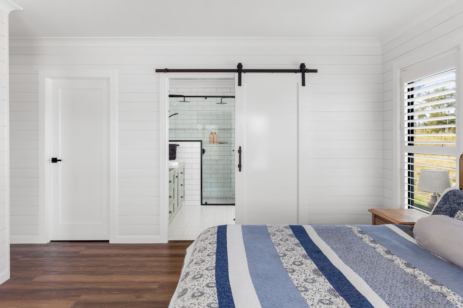 a bedroom with a sliding barn door leading to a bathroom .