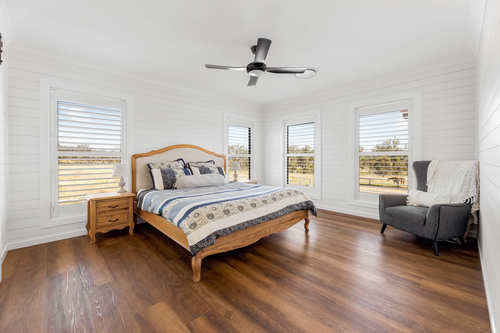 a bedroom with a bed , chair , nightstand and ceiling fan .