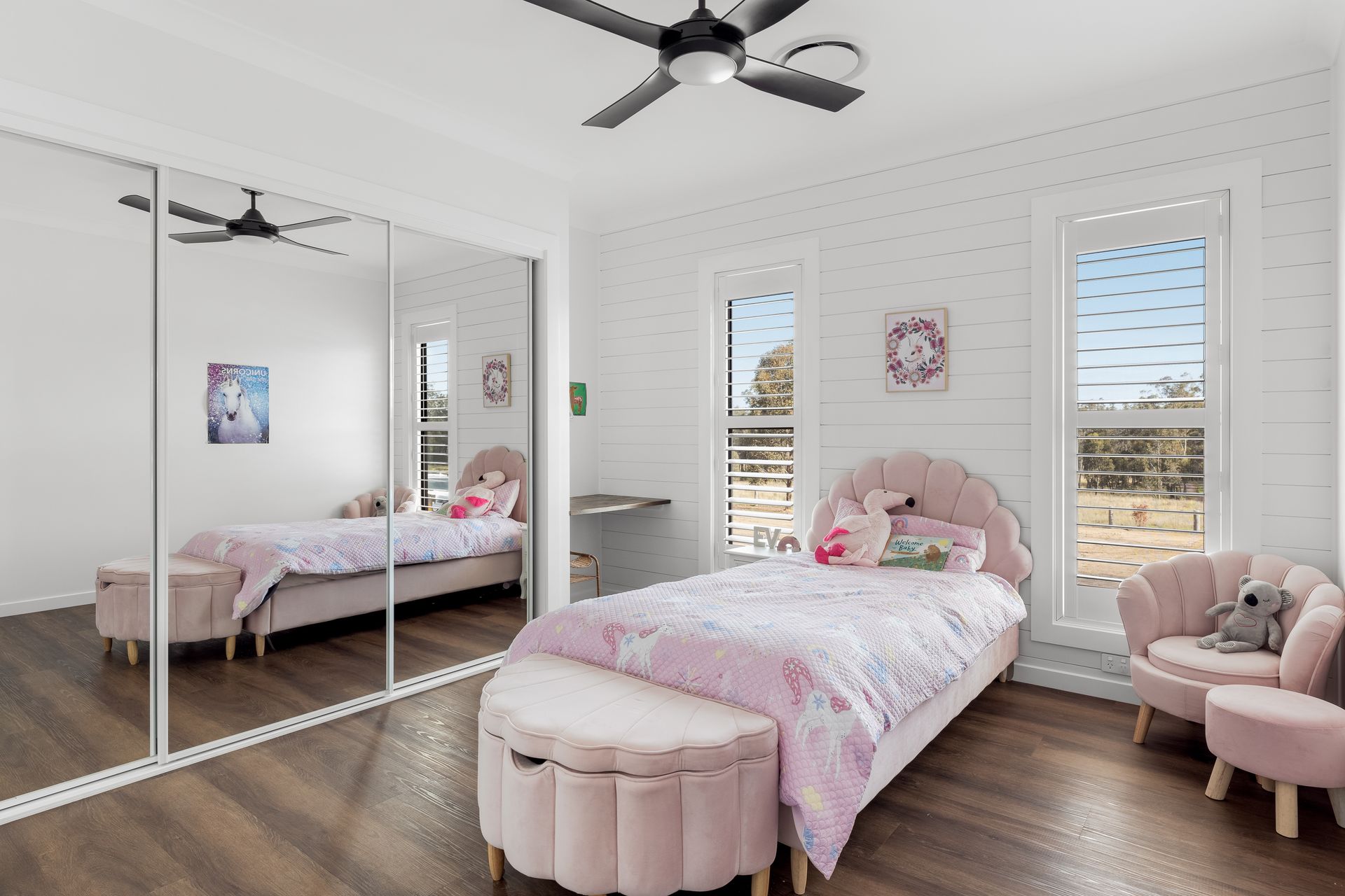 a bedroom with a bed , chair , ottoman , mirrors and a ceiling fan .