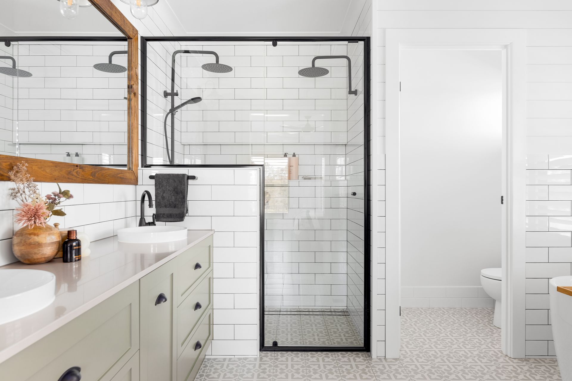 a bathroom with white tiles , a walk in shower , a sink and a toilet .