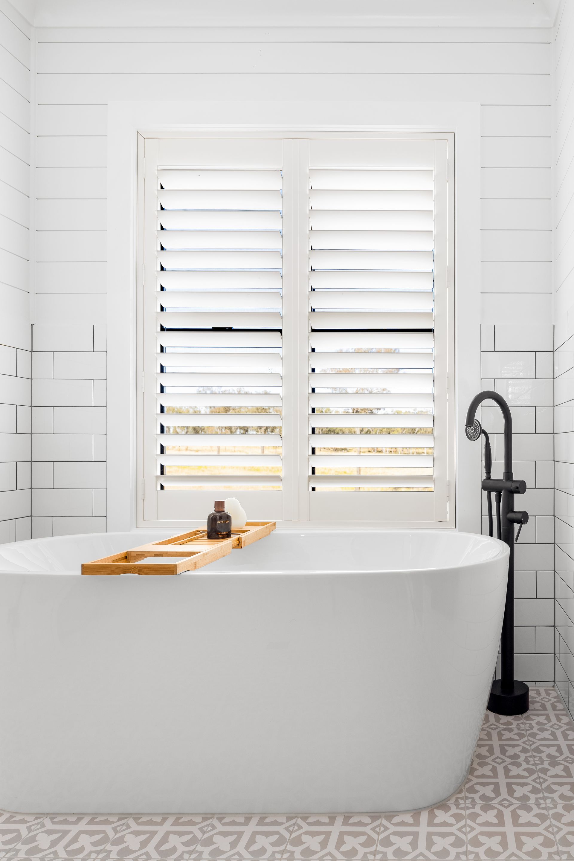 a bathroom with a bathtub and a window with shutters .