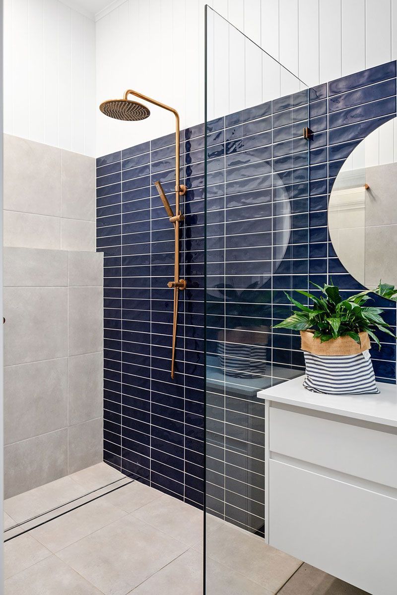 a bathroom with blue tiles , a walk in shower , a sink and a mirror .
