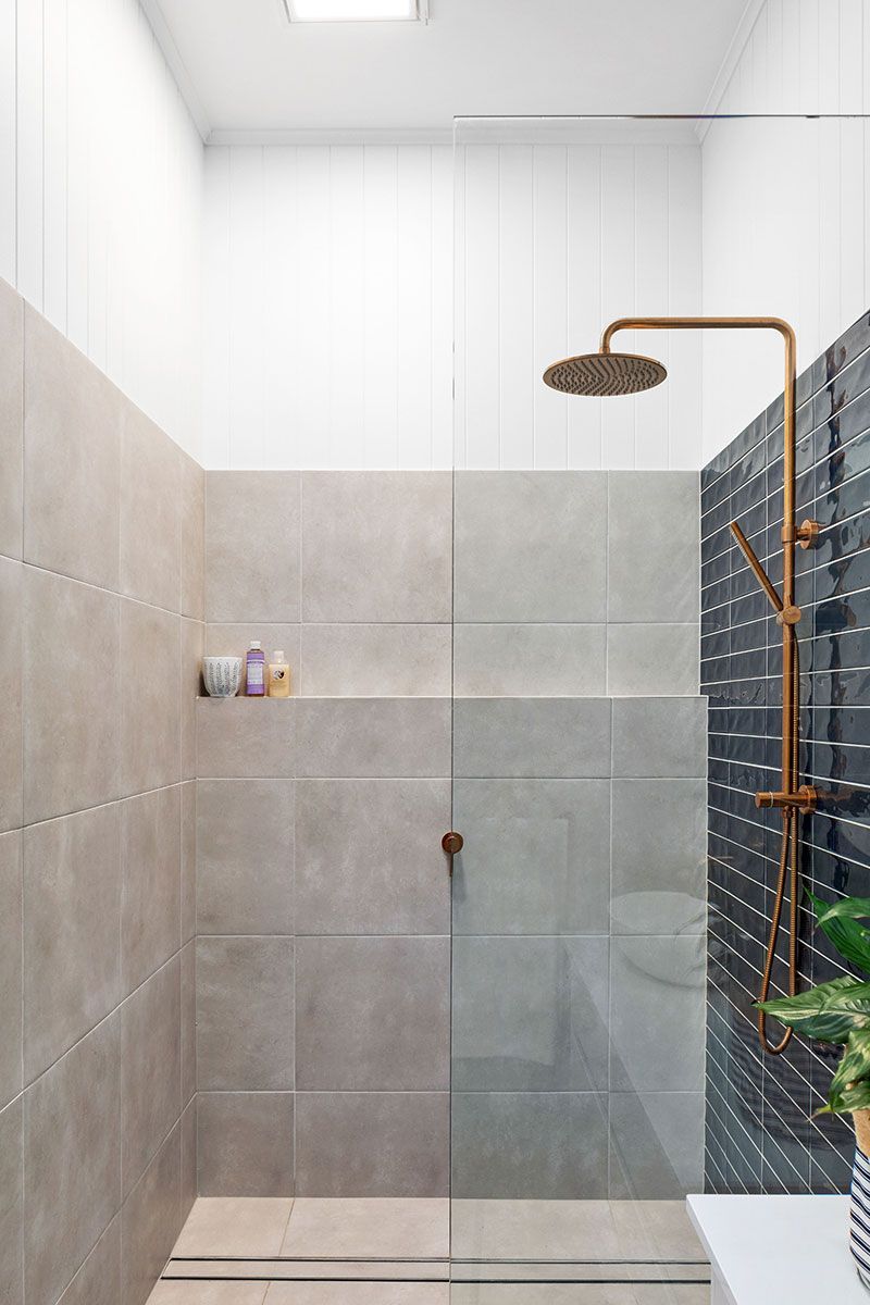 a bathroom with a walk in shower and a brass shower head .