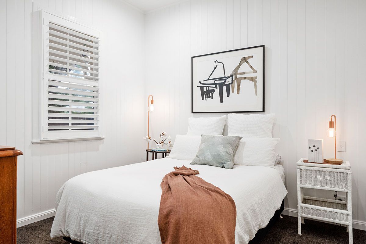 a bedroom with a bed , nightstand , lamp and a picture on the wall .