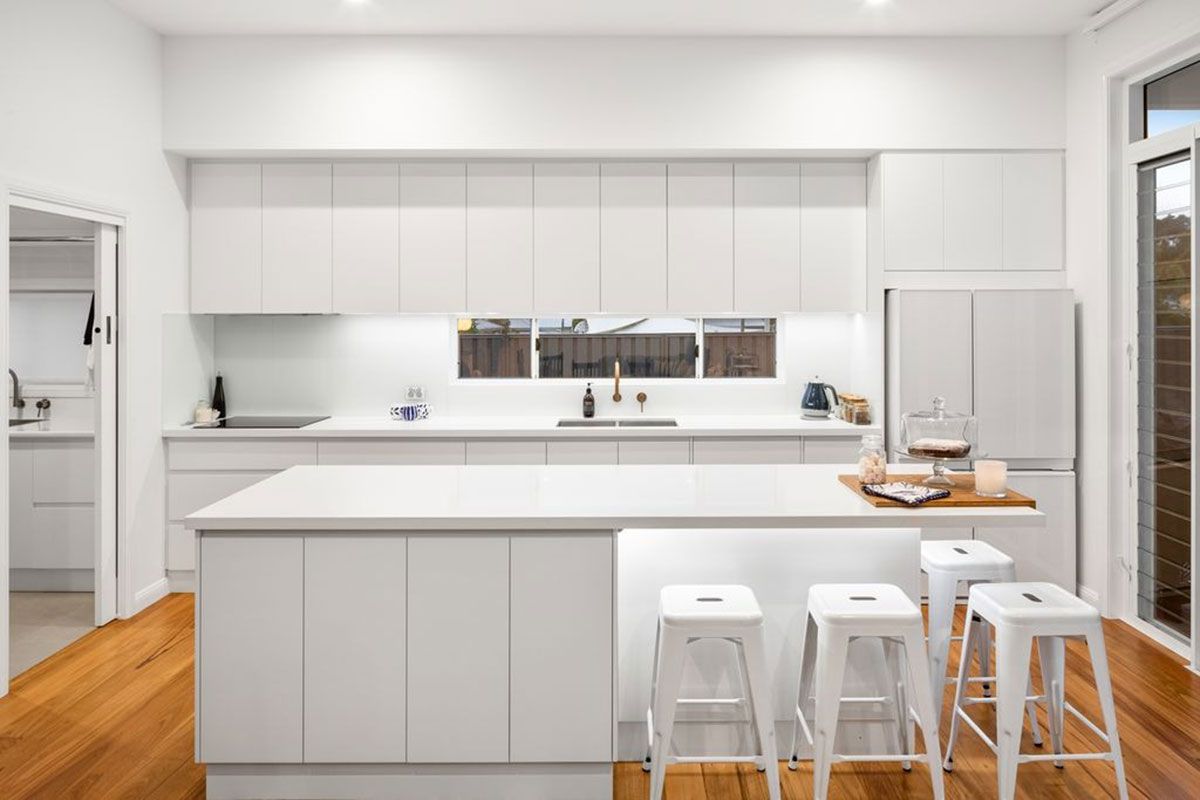 a kitchen with white cabinets and stools and a large island .