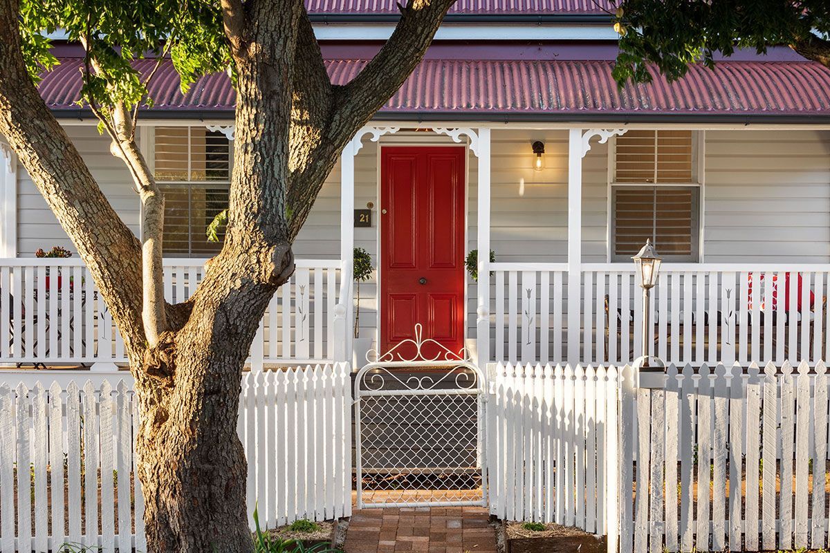 a white house with a red door and a white picket fence