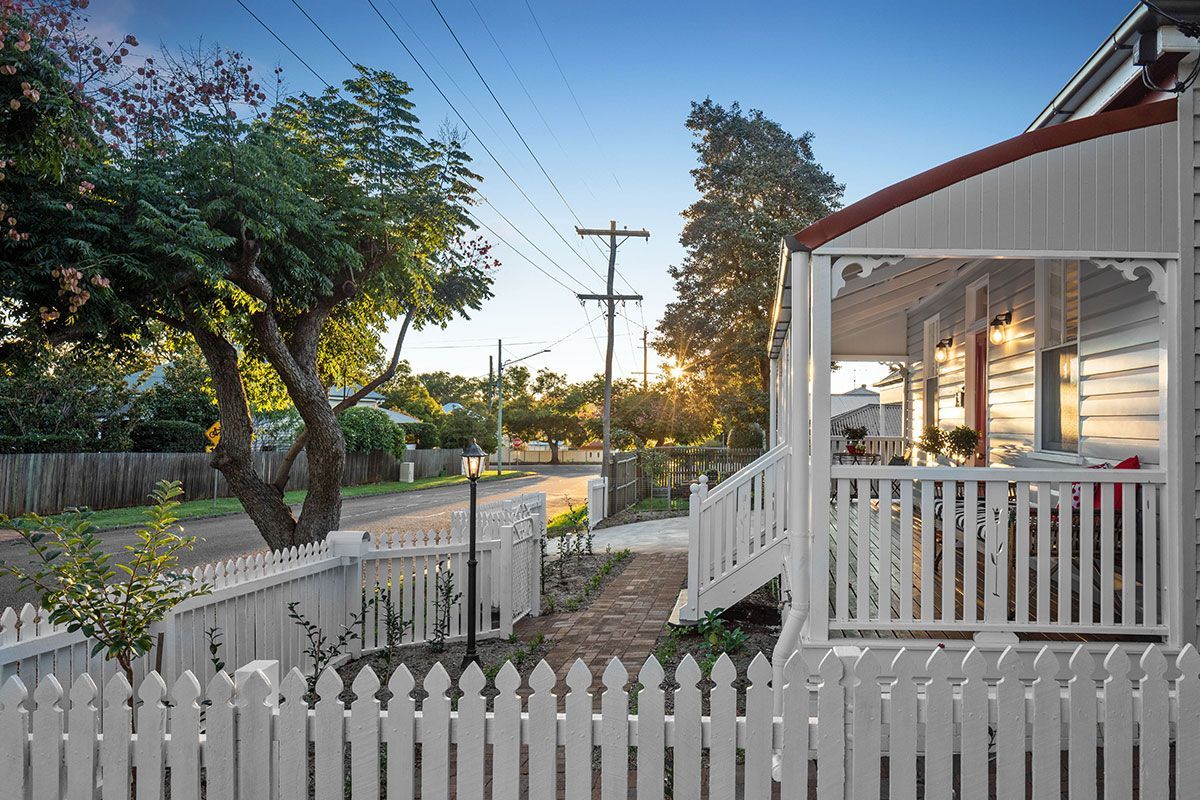a white picket fence surrounds a house with a porch .