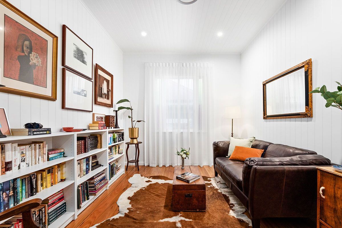a living room with a couch , bookshelves , and a cowhide rug .